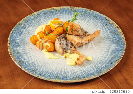 Crispy fried fish served with golden potato balls, creamy yellow sauce, microgreens, and a wedge of lemon on a rustic plate Crispy fried fish served with golden potato balls, creamy yellow sauce, microgreens, and a wedge of lemon on a rustic plate 129215650