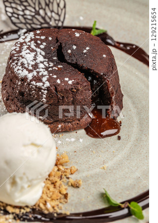 Classic chocolate lava cake with a rich molten center, dusted with powdered sugar and served with a scoop of vanilla ice cream and crumbled nuts Classic chocolate lava cake with a rich molten center, dusted with powdered sugar and served with a scoop of vanilla ice cream and crumbled nuts 129215654