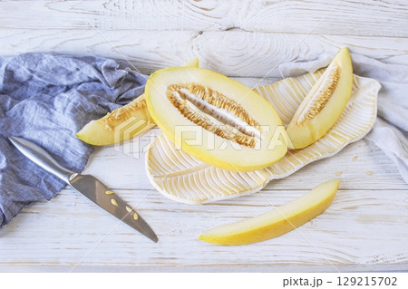 Cut ripe melon. Melon and knife on white wooden background. Top view. Beautiful still life. Cut ripe melon. Melon and knife on white wooden background. Top view. Beautiful still life. 129215702