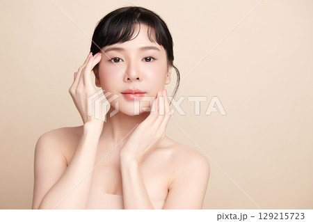 A beautiful young Asian woman with clean, fresh skin against a beige background. Skincare, facial treatment, cosmetology, beauty, and spa. An elegant portrait of an Asian woman. A beautiful young Asian woman with clean, fresh skin against a beige background. Skincare, facial treatment, cosmetology, beauty, and spa. An elegant portrait of an Asian woman. 129215723