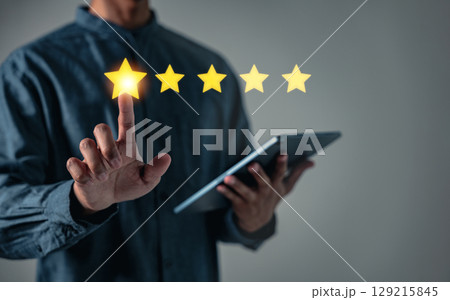 Customer satisfaction is key as a businessman adds a five star rating indicating best business rates, aiming to increase the company standing in the eyes of the customer Customer satisfaction is key as a businessman adds a five star rating indicating best business rates, aiming to increase the company standing in the eyes of the customer 129215845