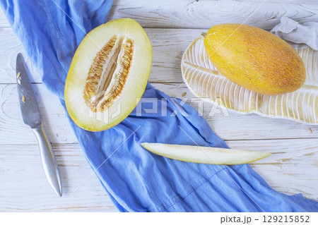 Cut ripe melon. Melon and knife on white wooden background. Top view. Beautiful still life. Cut ripe melon. Melon and knife on white wooden background. Top view. Beautiful still life. 129215852