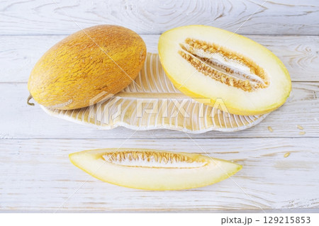 Cut ripe melon. Melon and knife on white wooden background. Top view. Beautiful still life. Cut ripe melon. Melon and knife on white wooden background. Top view. Beautiful still life. 129215853