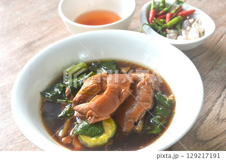 braised slice pork leg stew black Chinese herb soup and kale dipping  mixed spicy sour chili sauce on plate eat couple fresh garlic 129217191