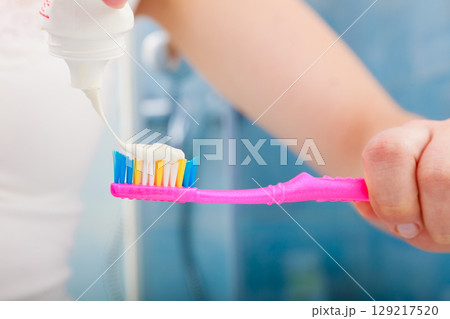 Woman hands putting toothpaste on toothbrush 129217520