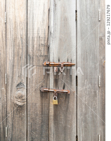 Rusty Padlock on Aged Wooden Door. 129217679
