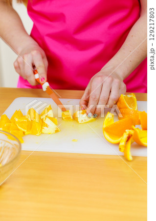 Woman housewife in kitchen cutting orange fruits Woman housewife in kitchen cutting orange fruits 129217803
