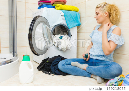 Woman wash laundry using detergent pods 129218035