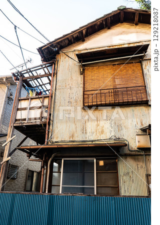 古い昭和建築、トタン作りの錆びた一軒家、鬱蒼とした二階建て狭小住宅 129218087
