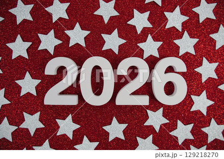Happy New Year 2026 number and silver star confetti on red glitter background Happy New Year 2026 number and silver star confetti on red glitter background 129218270