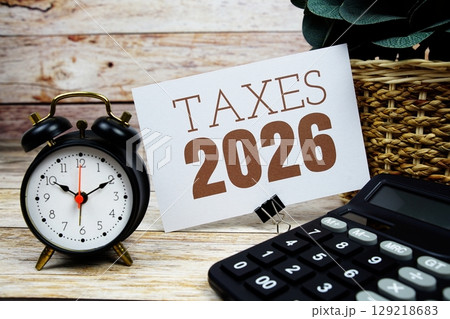 Taxes 2026 text with alarm clock and calculator on wooden background Taxes 2026 text with alarm clock and calculator on wooden background 129218683