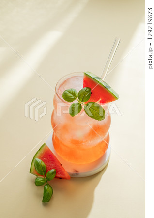 Watermelon mojito cocktail with ice and mint in a glass on a yellow background with shadow. 129219873