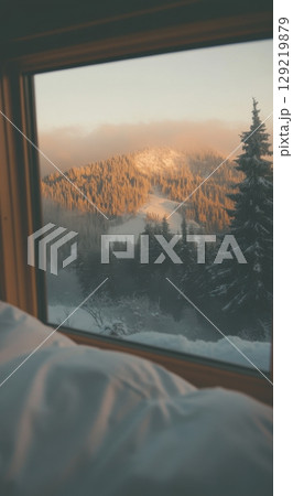 Winter forest and snowy peaks seen from a warm bedroom window at sunrise in a mountain retreat Winter forest and snowy peaks seen from a warm bedroom window at sunrise in a mountain retreat 129219879