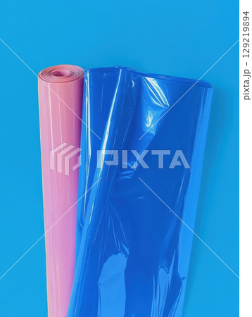 Shiny plastic sheet with blue, purple, orange tones folded over bright background, minimal design 129219894