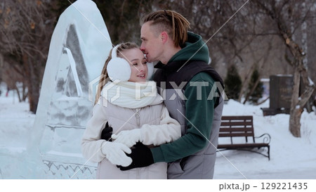 Loving couple embracing near intricate ice sculpture, snowflakes softly falling around romantic silhouettes in serene winter landscape, embodying intimate connection Loving couple embracing near intricate ice sculpture, snowflakes softly falling around romantic silhouettes in serene winter landscape, embodying intimate connection 129221435
