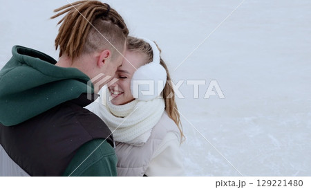 Loving couple embracing, wearing winter attire and earmuffs, sharing intimate connection amid snowy landscape, expressing warm emotional bond Loving couple embracing, wearing winter attire and earmuffs, sharing intimate connection amid snowy landscape, expressing warm emotional bond 129221480