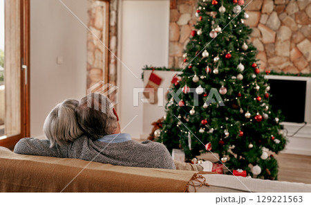 Senior couple, christmas and hug from back view relax on sofa in living room with christmas tree. Love, support and festive holiday celebration or senior man and woman relax on couch together at home 129221563