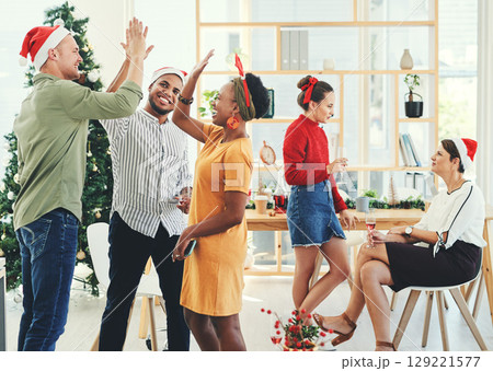 Christmas, party and high five with business people having fun in their office together during the festive season. Team, motivation and celebration with a man and woman colleague group at work 129221577