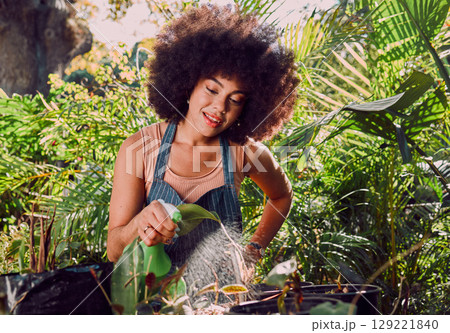 Black woman, water and spray bottle for plants, garden and eco friendly outdoor flowers. Agriculture, sustainability or African American female gardening, growth or liquid for ecology, flora or relax Black woman, water and spray bottle for plants, garden and eco friendly outdoor flowers. Agriculture, sustainability or African American female gardening, growth or liquid for ecology, flora or relax 129221840