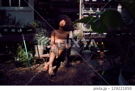 Zen, nature and black woman in a garden to relax with freedom, calm and peace in a backyard for fresh air. Green plants, environment and African girl resting or relaxing after gardening in shadows Zen, nature and black woman in a garden to relax with freedom, calm and peace in a backyard for fresh air. Green plants, environment and African girl resting or relaxing after gardening in shadows 129221850