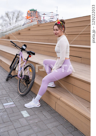 Portrait of Sporty Woman with her bicycle for vacation, holiday and happiness in park or outdoor. Female person on bench for rest, relax and break 129222033