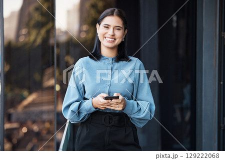 Phone, portrait and happy with a business woman typing a text message while standing outdoor on an office balcony. Social media, smile and communication with a female employee sending a mobile email 129222068