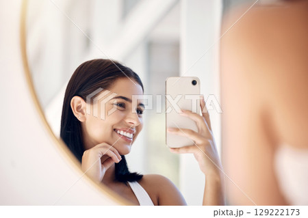 Phone, happy and selfie of woman in bathroom with smile for natural social media beauty in mirror. Reflection, happiness and skincare of wellness influencer girl with smartphone in the morning. 129222173