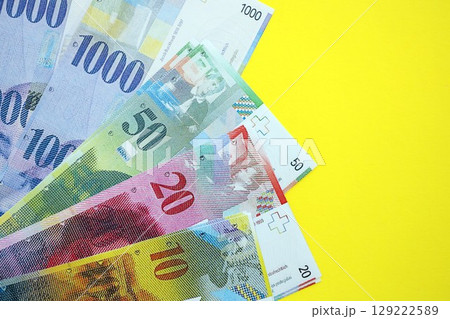 Swiss franc banknotes on yellow. The current francs money bills lies on table in big amount Swiss franc banknotes on yellow. The current francs money bills lies on table in big amount 129222589