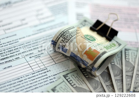 Big amount of United States hundred dollar bills in bunch on table with tax return form 129222608