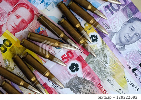 Philippines peso currency money bills and rifle bullets. The concept of warfare and gun selling 129222692