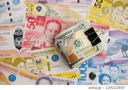 Philippines peso currency money bills and bunch of us dollar banknotes. The concept of economics and currency exchange Philippines peso currency money bills and bunch of us dollar banknotes. The concept of economics and currency exchange 129222697