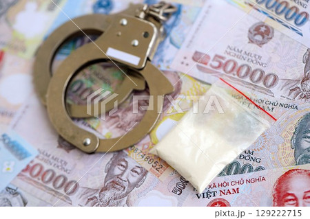 Vietnamese dong currency money bills and cocaine pack with handcuffs. The concept of drug crimes 129222715