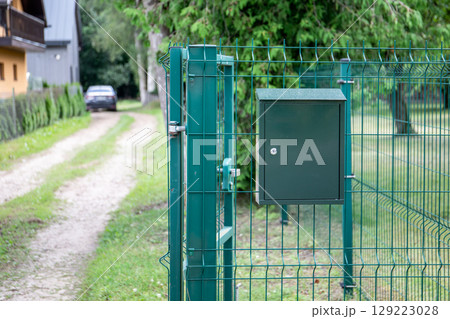 Green Mailbox Mounted on Metal Fence by Country Road Green Mailbox Mounted on Metal Fence by Country Road 129223028
