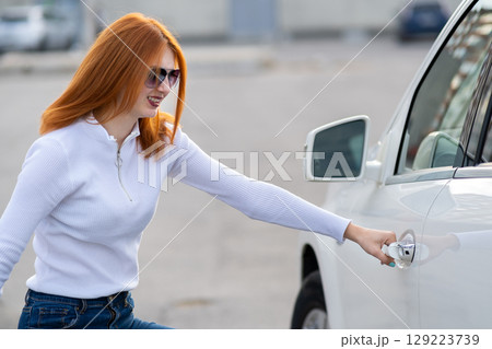 A woman trying to open closed car doors. A woman trying to open closed car doors. 129223739
