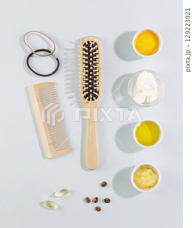 Hair care flat lay with wooden combs, ingredients for mask for hair, vitamins for health hair on a blue background. Natural beauty products for hair 129223921