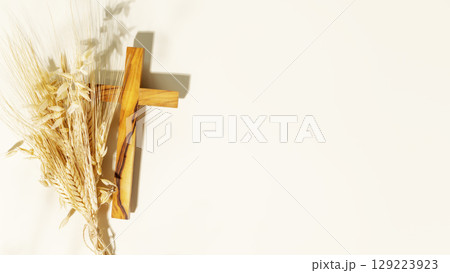 Wooden crucifixion with bouquet of wheat and rye on light background with copy space. Religion background suitable for faith religion, christian holidays, Easter, Redeemer, the Feast of Corpus Christi 129223923