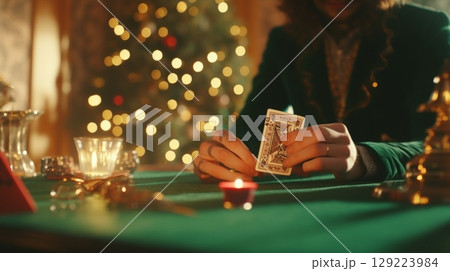 Close-up of hands holding playing cards in a poker game at green table in casino interior 129223984