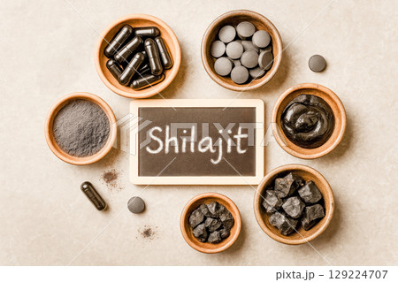 Various Forms Of Shilajit Displayed In Wooden Bowls Around Chalkboard Label On Neutral Background. Concept Of Ayurvedic Wellness, Natural Supplement Trends, And Holistic Health Visuals For Eco Brands 129224707