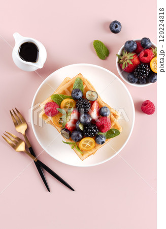 Belgian waffles with fresh strawberry and maple syrup on pink background. Top view.  129224818