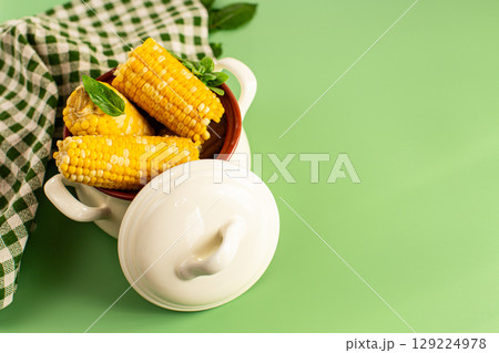 Hot corn cobs with greens on a green background 129224978