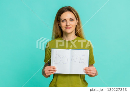 Adult woman proudly showing notebook page with big word done written after completing important task Adult woman proudly showing notebook page with big word done written after completing important task 129227258