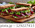 Healthy beetroot sandwiches with goat cheese and arugula on wooden cutting board 129227413
