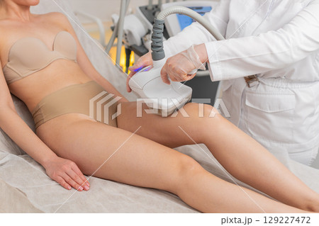 Doctor makes woman cavitation LPG vacuum roller massage on legs, correction figures in spa clinic Doctor makes woman cavitation LPG vacuum roller massage on legs, correction figures in spa clinic 129227472