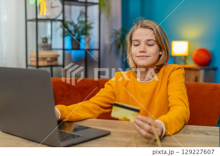 Teenager boy planning online purchase on laptop entering credit card details and ordering from home 129227607