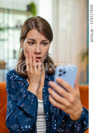 Sad displeased Caucasian woman using smartphone receive bad news, fortune loss fail, deadline, virus Sad displeased Caucasian woman using smartphone receive bad news, fortune loss fail, deadline, virus 129227608
