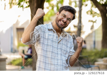 Excited happy man traveler shouting, celebrating success, winning clenching fists walking on street 129227618