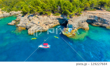 Aerial view on coast with rocks and forest. Boat and kayaks in the bay.  129227684