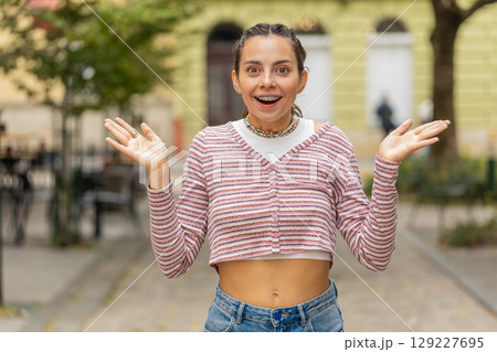 Excited Caucasian young woman tourist walking on urban city street expresses amazement, wow emotion 129227695