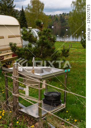 Outdoor stainless steel sink with faucet and kitchen utensils at lakeside camping site 129227875