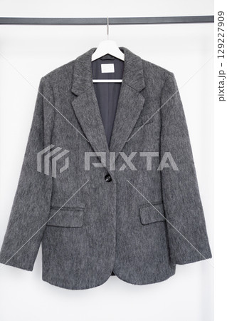 Gray oversized blazer made of faux wool and polyester hanging on hanger for fashion retail Gray oversized blazer made of faux wool and polyester hanging on hanger for fashion retail 129227909